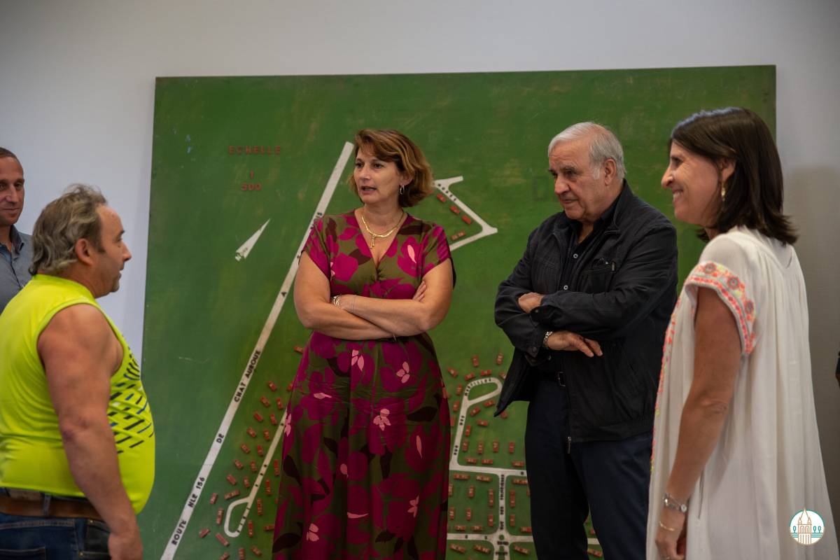 The mayor and the president listen attentively to the story of the model's discovery